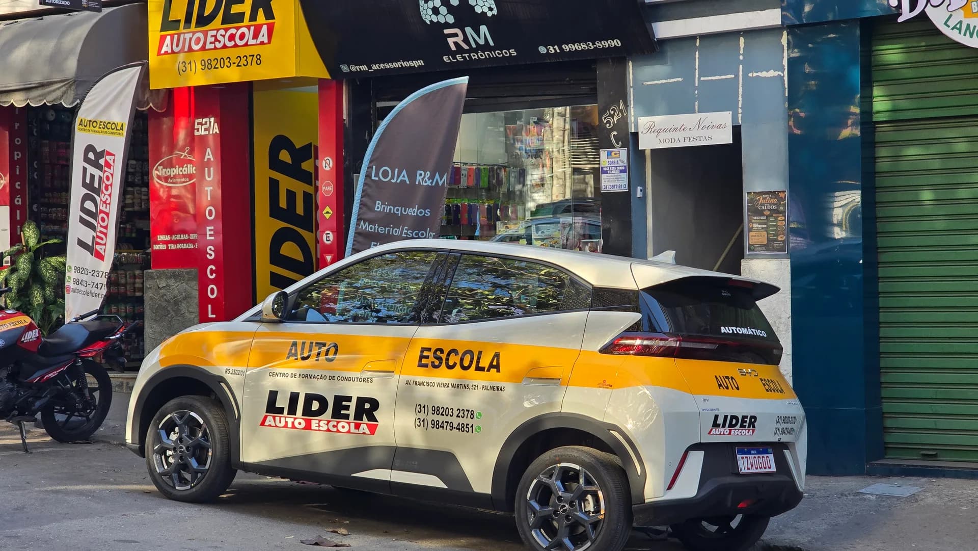 Carro automático da Líder, visto de lado e por trás, em frente à autoescola.