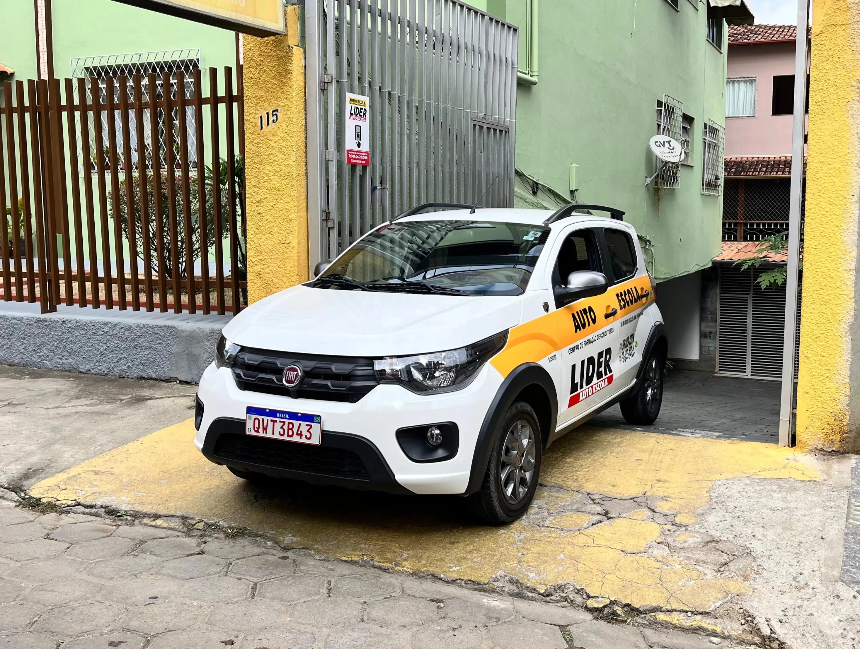 Carro da autoescola na entrada do escritório da autoescola.